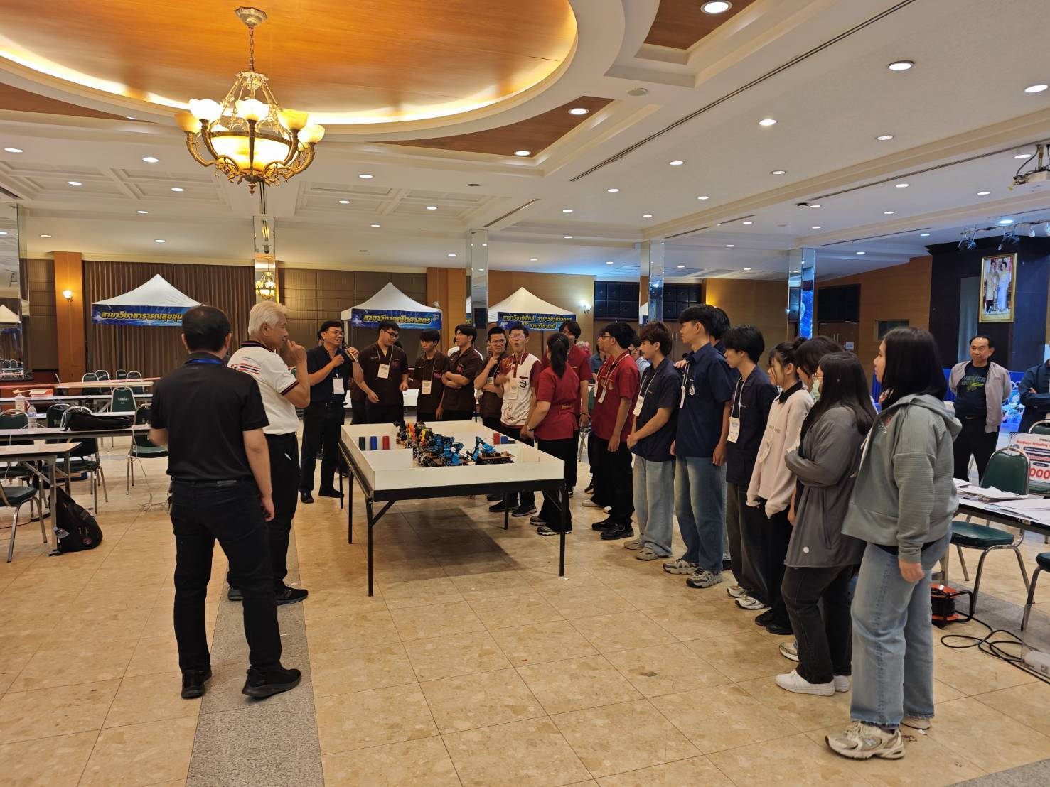 Organisers briefing student teams gathered around the robot competition arena at the Northern Roboding Challenge 2026