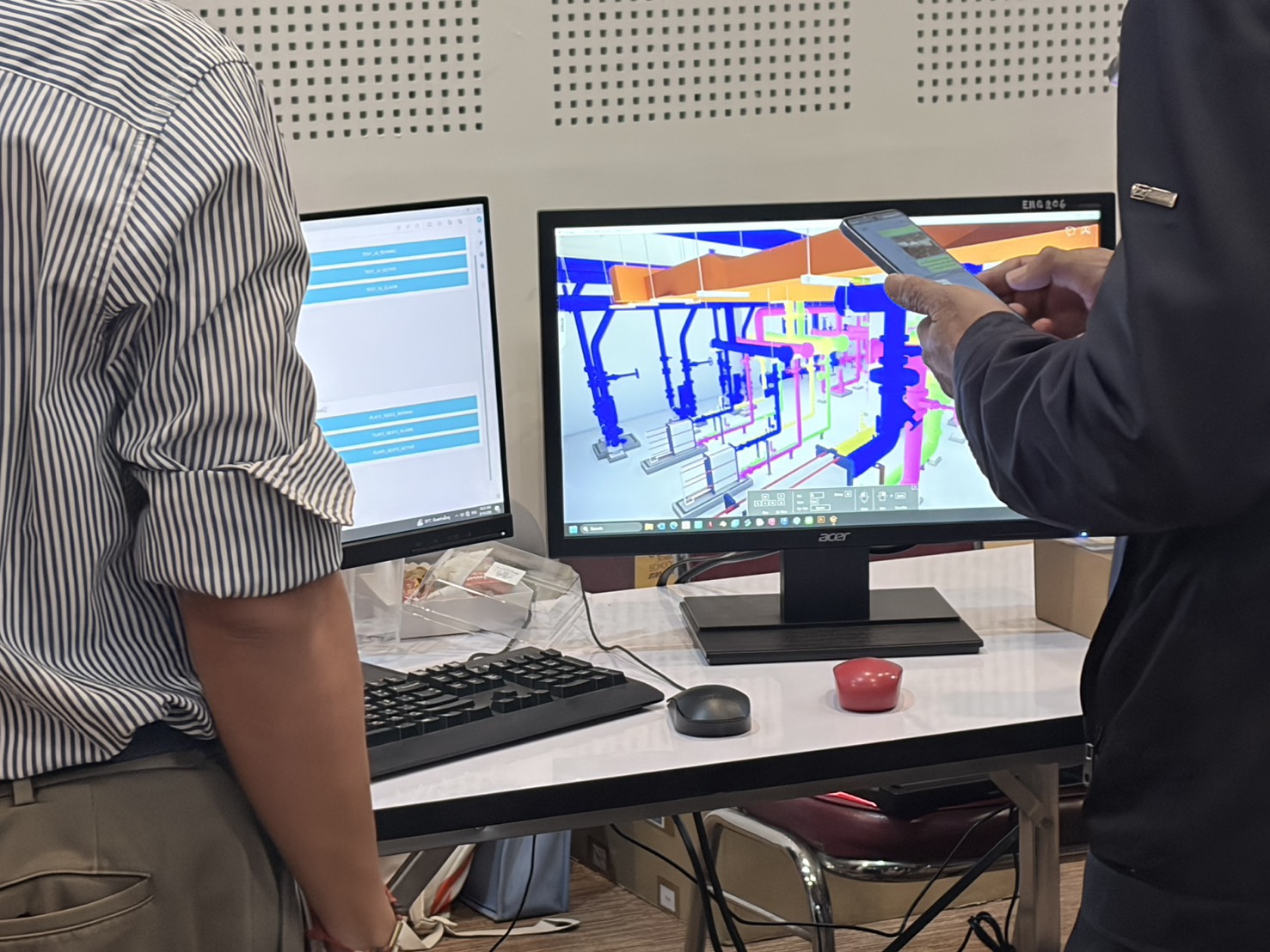 Two participants reviewing a colour-coded 3D BIM piping model on a monitor during the Digital Twin bootcamp