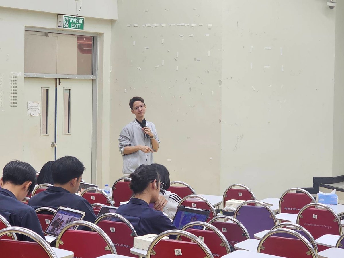 The speaker standing with a microphone as he addresses the students